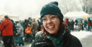 Auf dem Bild ist Saphir Ben Dakon zu sehen. Sie steht draussen im Schnee und lacht in die Kamera.